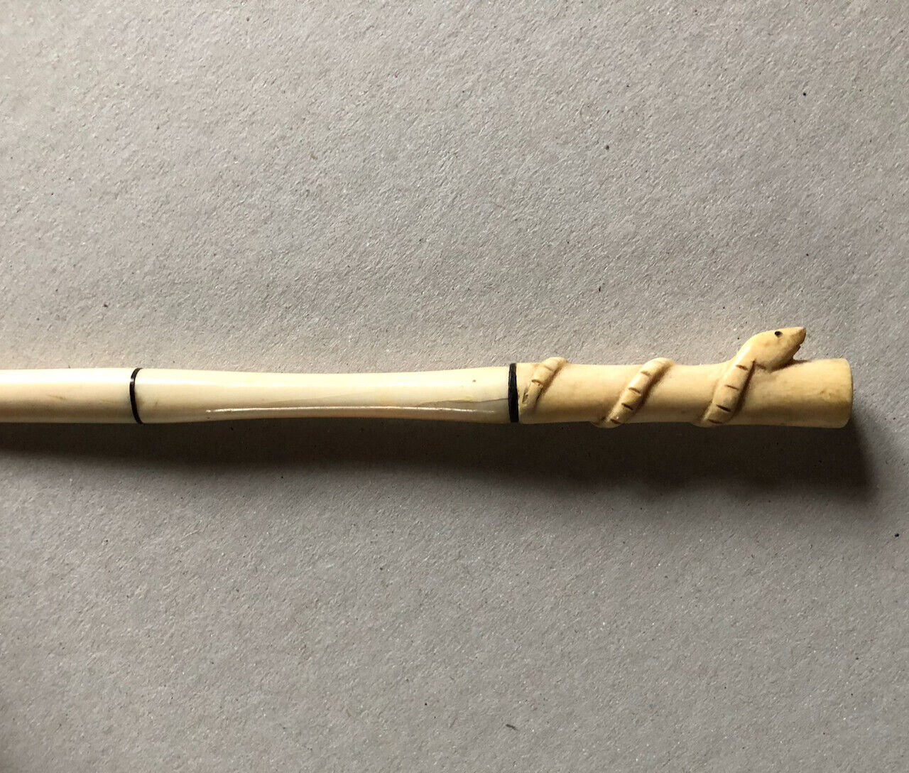 Fume-cigarette en os sculpté d'un serpent enroulé — circa 1930.